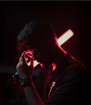 Silhouette of a man posing with red neon lighting, creating a moody, cinematic effect.