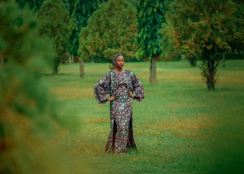 Free Elegant woman in traditional attire standing in a green park with trees. Stock Photo