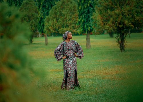 Free Woman in traditional African attire posing confidently in a lush green park. Stock Photo