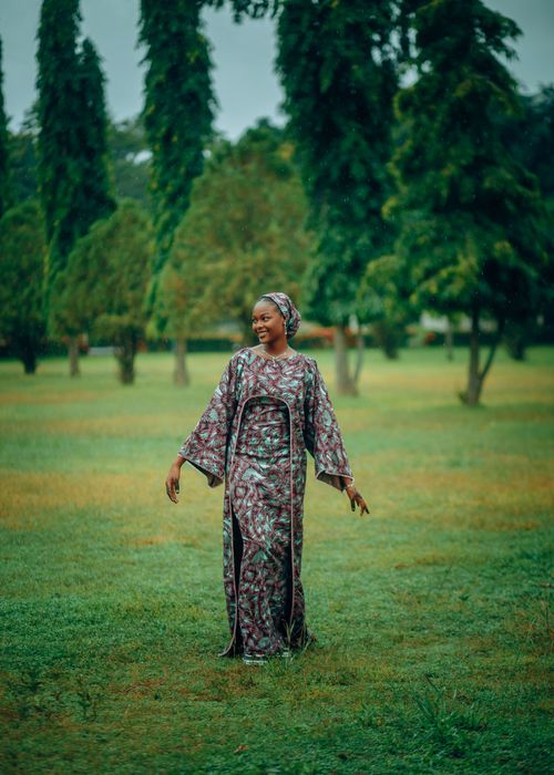 Free A woman in colorful traditional clothing poses joyfully in a vibrant green park. Stock Photo