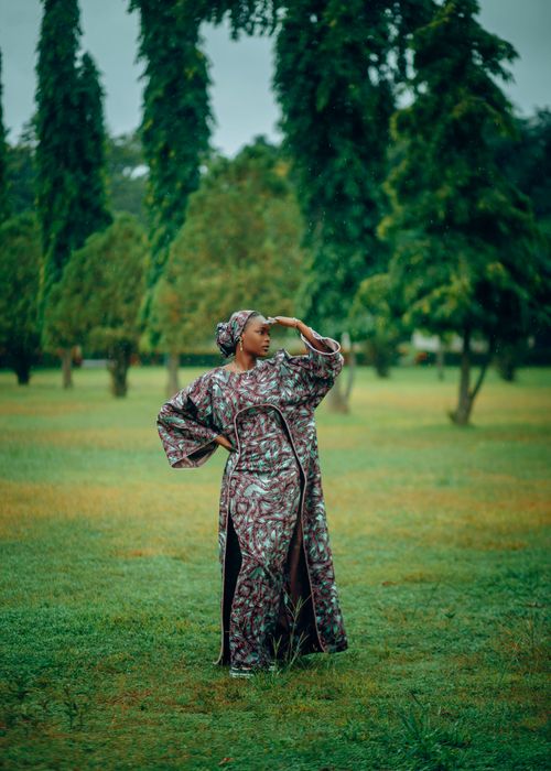 Free Elegant woman in traditional attire poses amidst vibrant green trees, evoking serenity and cultural richness. Stock Photo