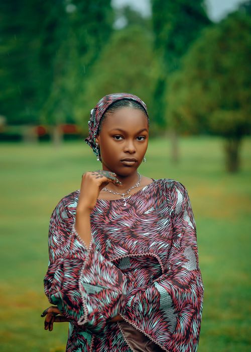 Free A woman in traditional attire poses in a lush garden, exuding elegance and cultural richness. Stock Photo