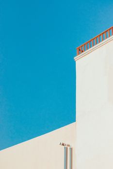 A minimalist architectural design of a beach house under a clear blue sky, featuring clean lines and pastel hues.