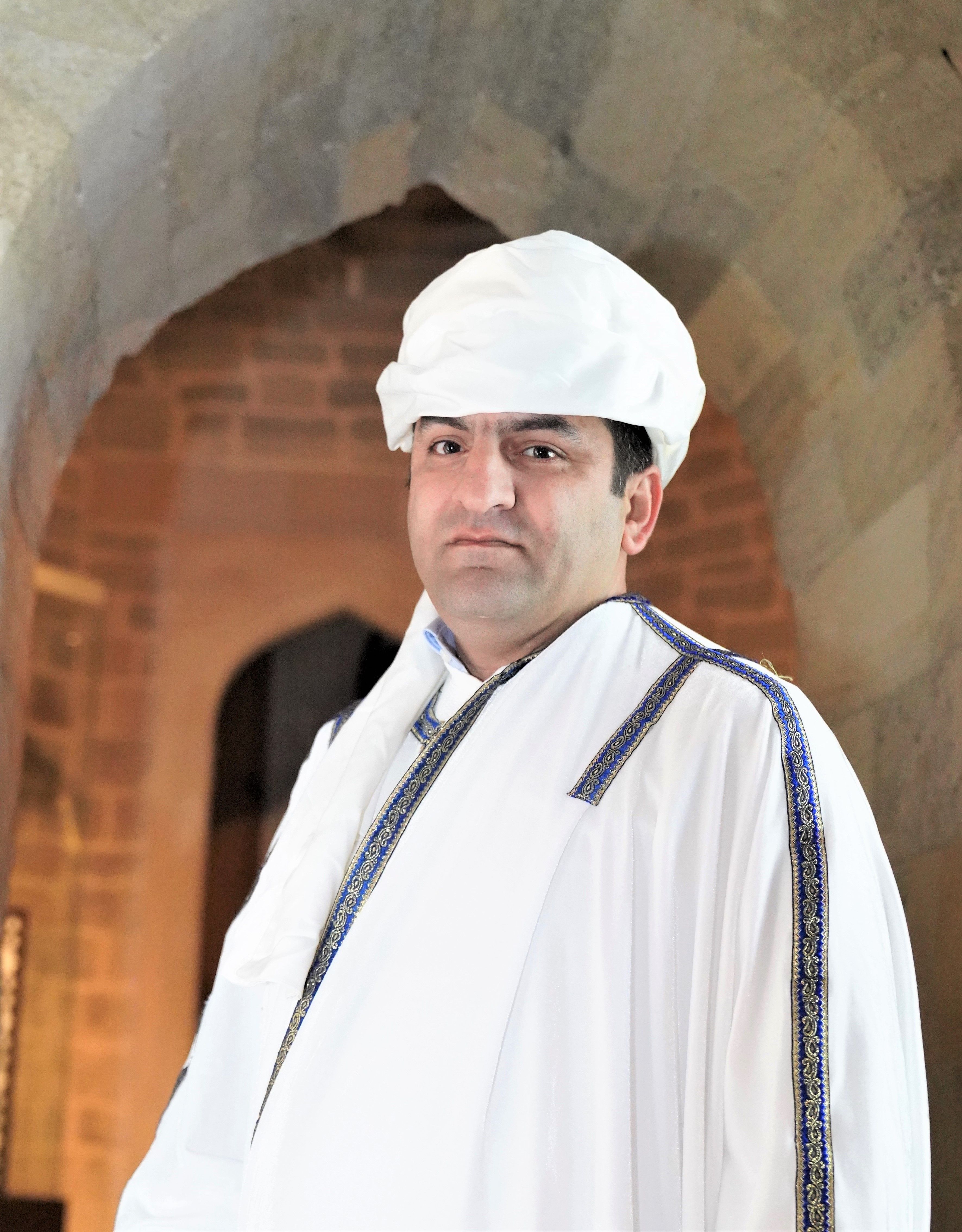 Portrait of a man wearing traditional Middle Eastern clothing in an indoor setting.