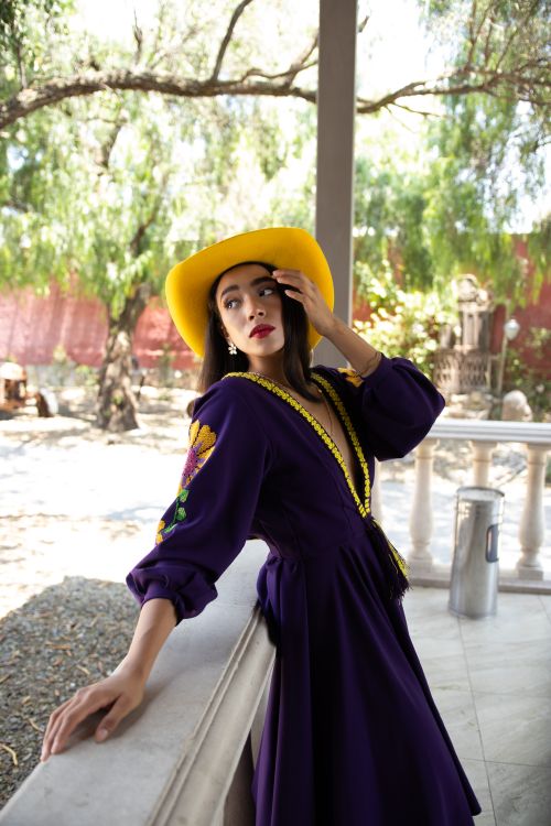 Free Elegant woman in a vibrant outdoor setting wearing a yellow hat and purple dress. Stock Photo