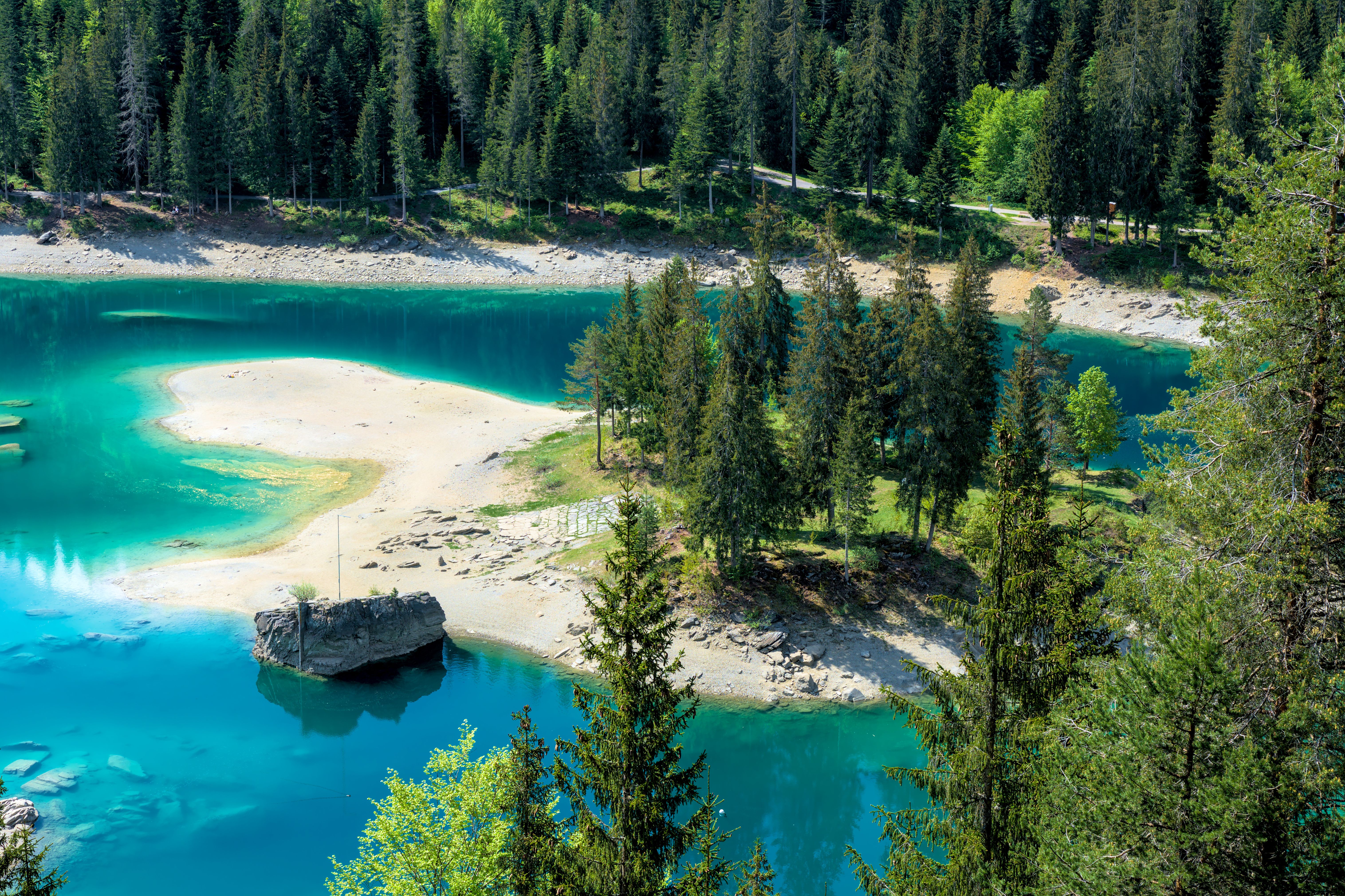 Breathtaking aerial view of Caumasee's turquoise waters and surrounding forest in the Swiss Alps. - Lago Cauma