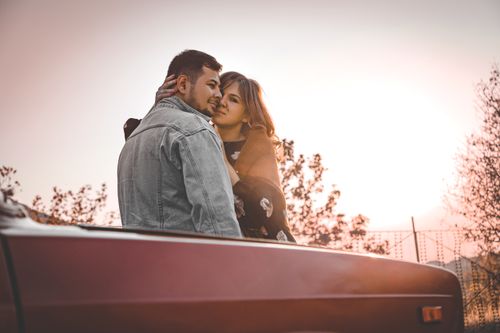 Free A couple shares an intimate moment, embracing beside a truck at sunset, radiating love. Stock Photo
