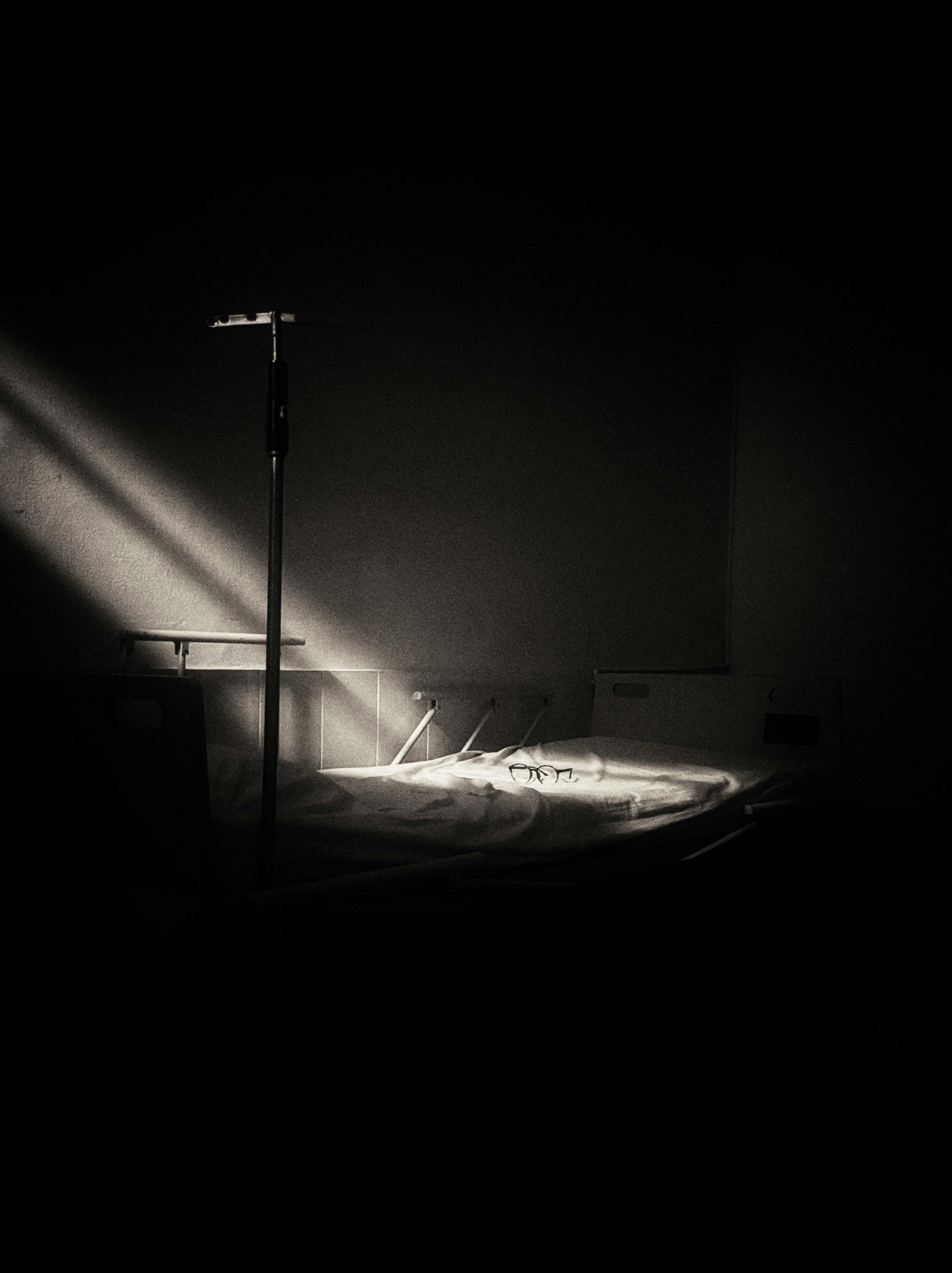 Free Black and white hospital room, dramatic light highlighting an empty bed, evokes solitude. Stock Photo
