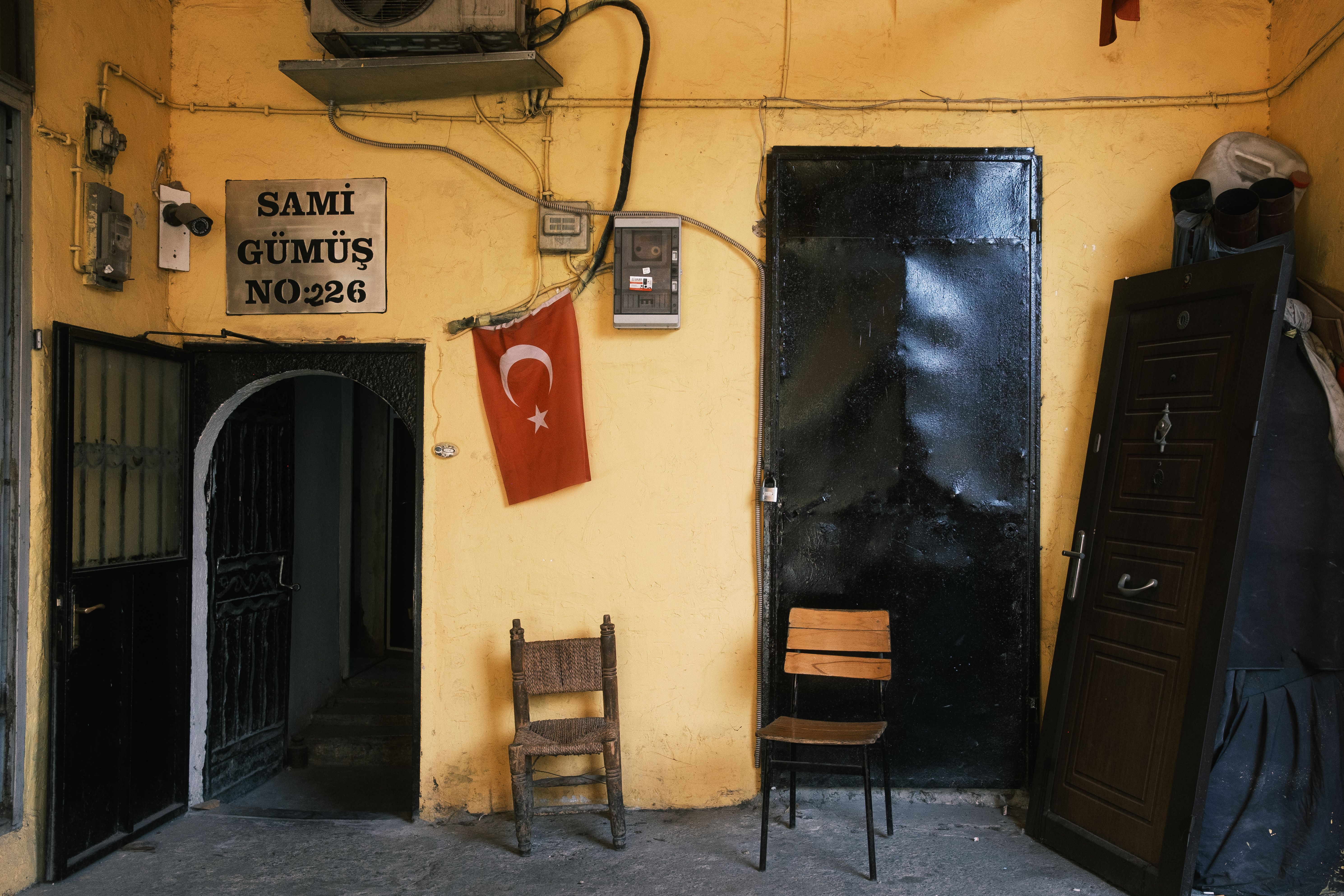 Authentic Turkish alleyway featuring old chairs, a Turkish flag, and a rustic building facade.