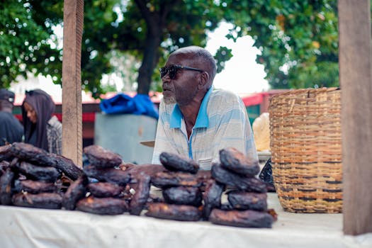 Elderly man selling goods at an outdoor market stall with woven baskets.