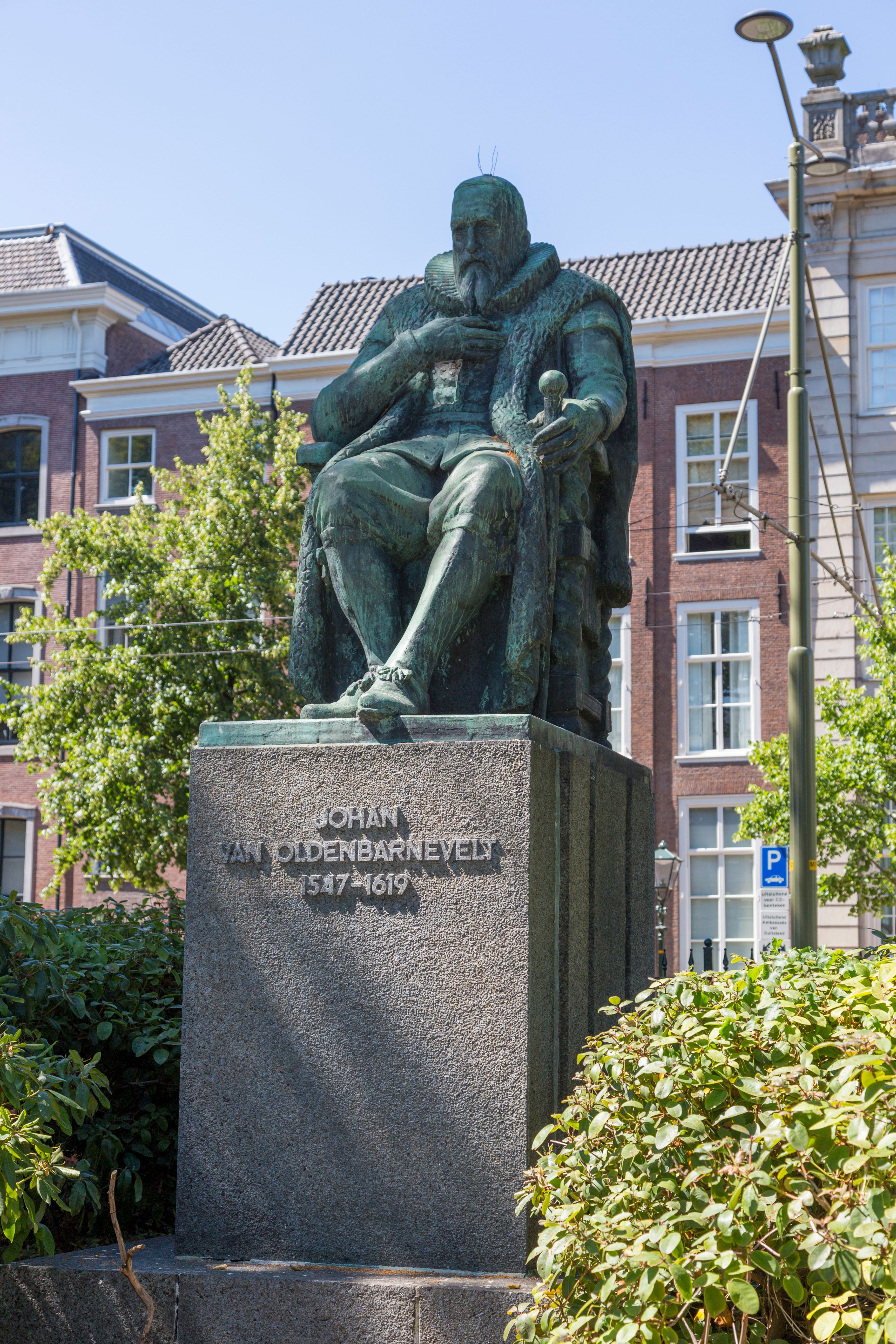 Bronze statue of Johan van Oldenbarnevelt in Amsterdam on a sunny day, reflecting historic architecture.