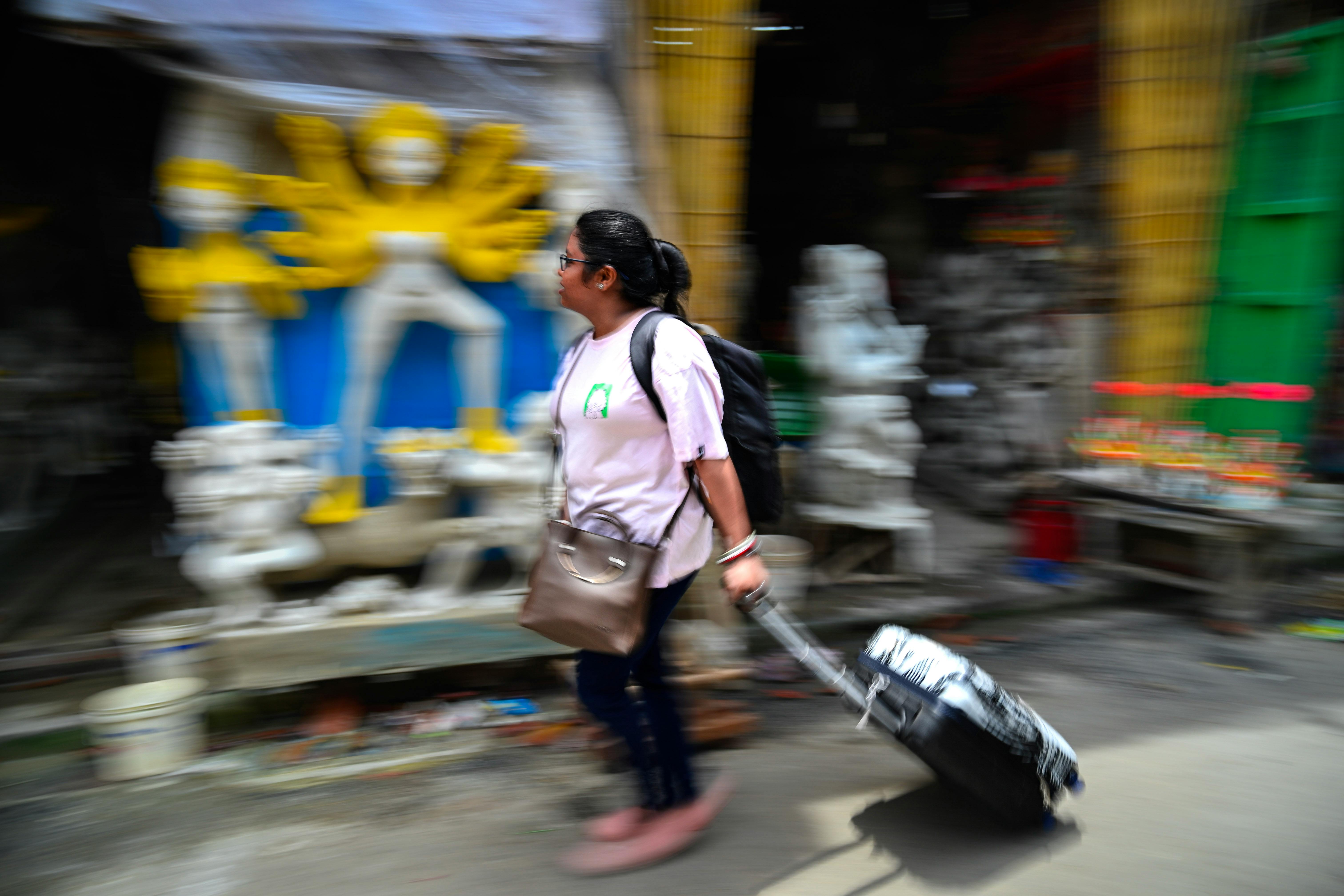 免费 在印度加尔各答，一名女子走过一座色彩斑斓的杜尔迦女神像，营造出充满活力的动态模糊效果。 素材图片