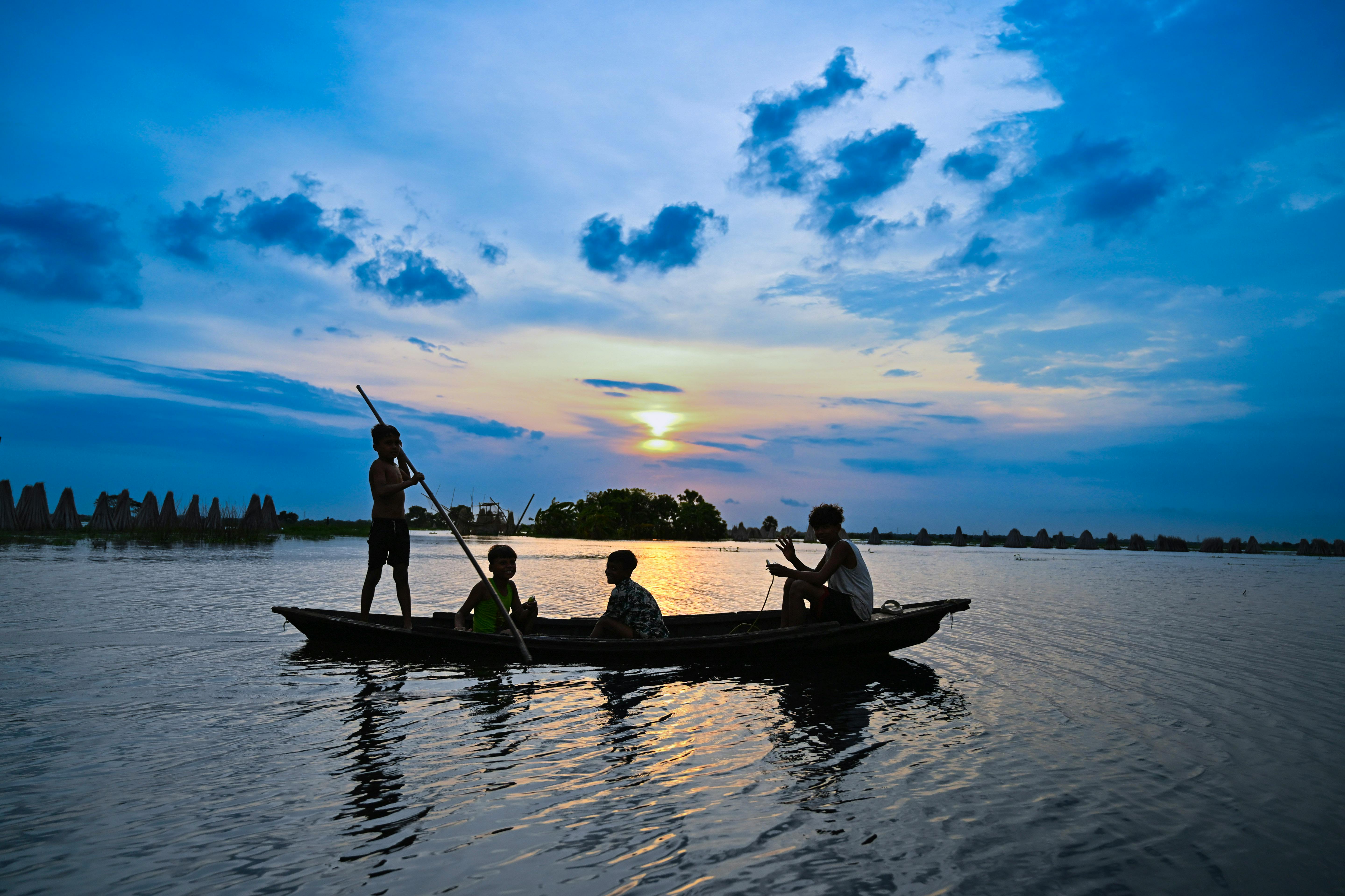 免费 在印度西孟加拉邦，傍晚时分，人们在船上悠闲地乘船，映衬着绚丽的日落，构成一幅美丽的剪影。 素材图片