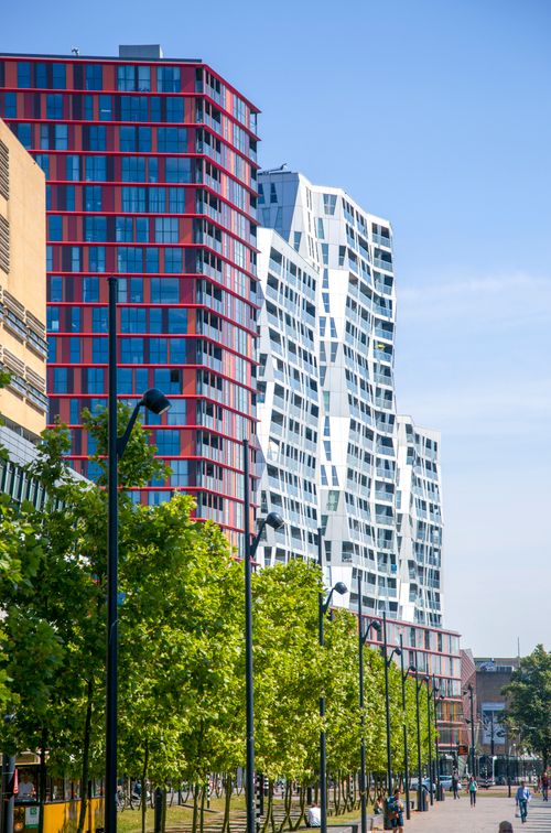 Free Contemporary city buildings with trees lining a vibrant street under a blue sky. Stock Photo