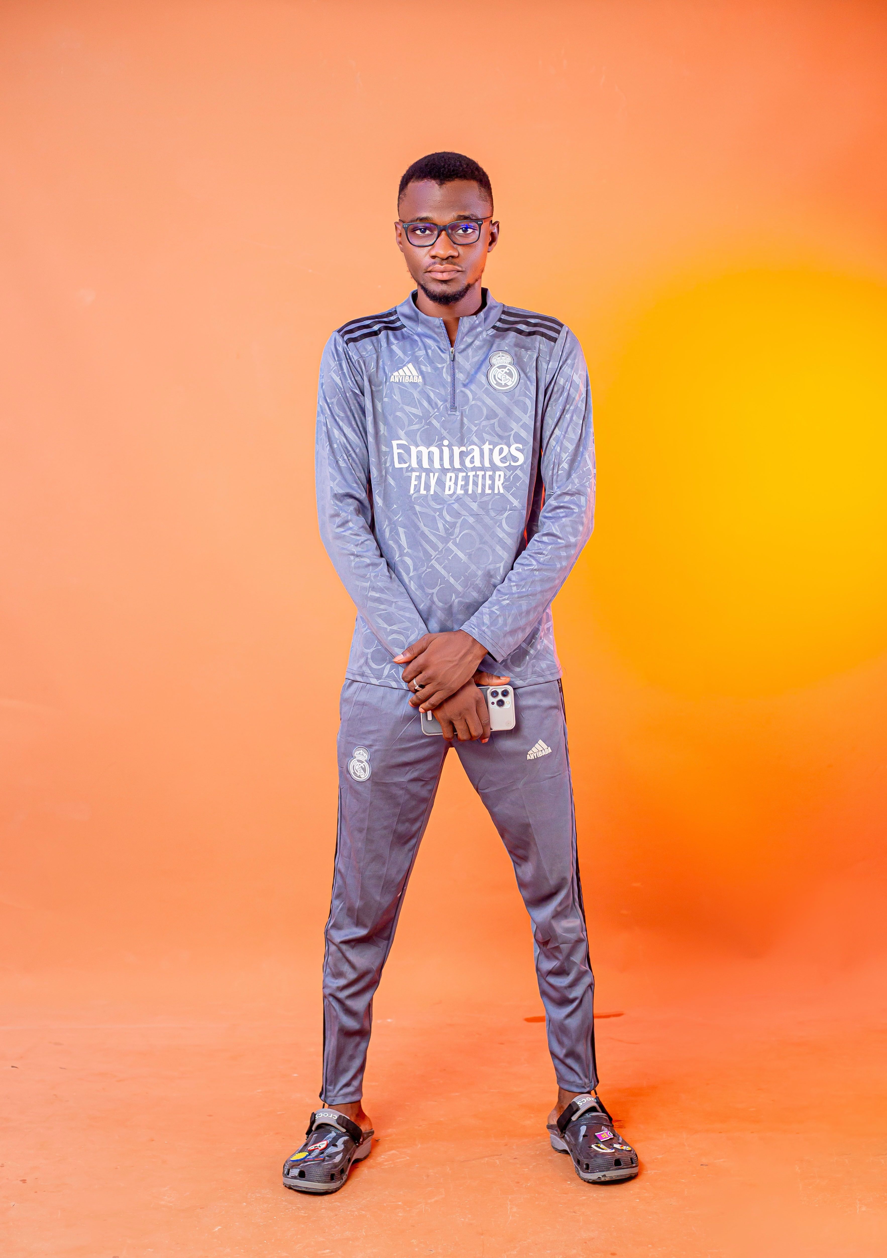 Confident young man in sportswear holding smartphone on orange background