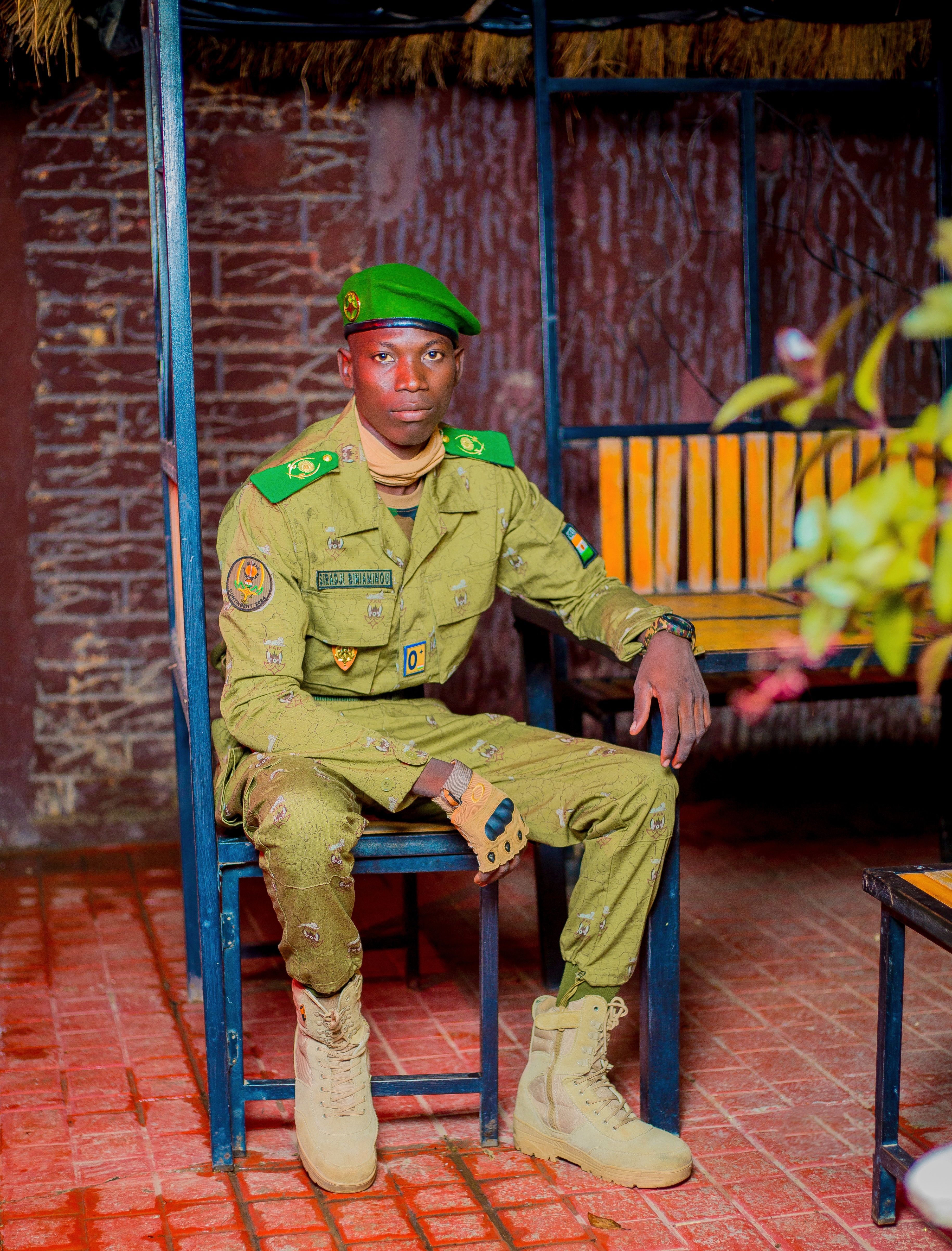 A soldier in full uniform sitting indoors on a chair.