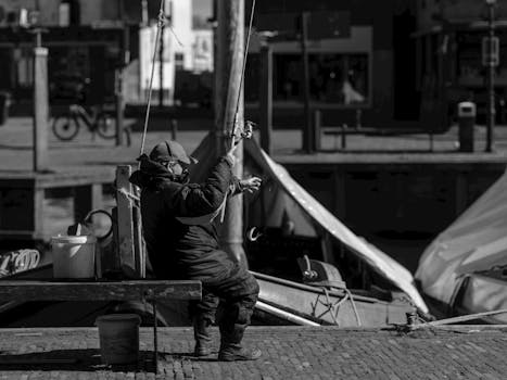 Fisherman using a rod at Bunschoten-Spakenburg quay in serene setting.