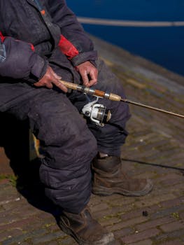 A fisherman sits by the quay in Bunschoten-Spakenburg, holding a fishing rod.