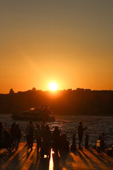 Silhouetted figures at sunset by the Bosphorus in Istanbul, Turkey.