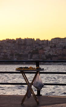 Serene sunset over a city skyline by the waterfront, featuring a small snack stand in the foreground.