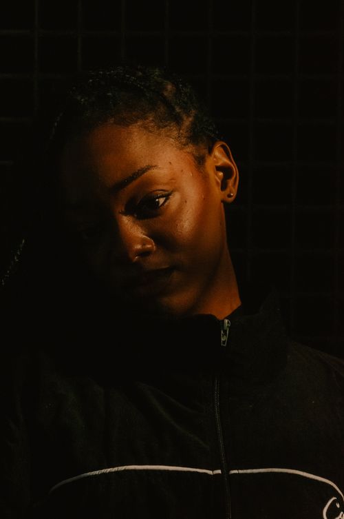 Free Dramatic low-light portrait of a young woman with a thoughtful expression, taken in Johannesburg, South Africa. Stock Photo
