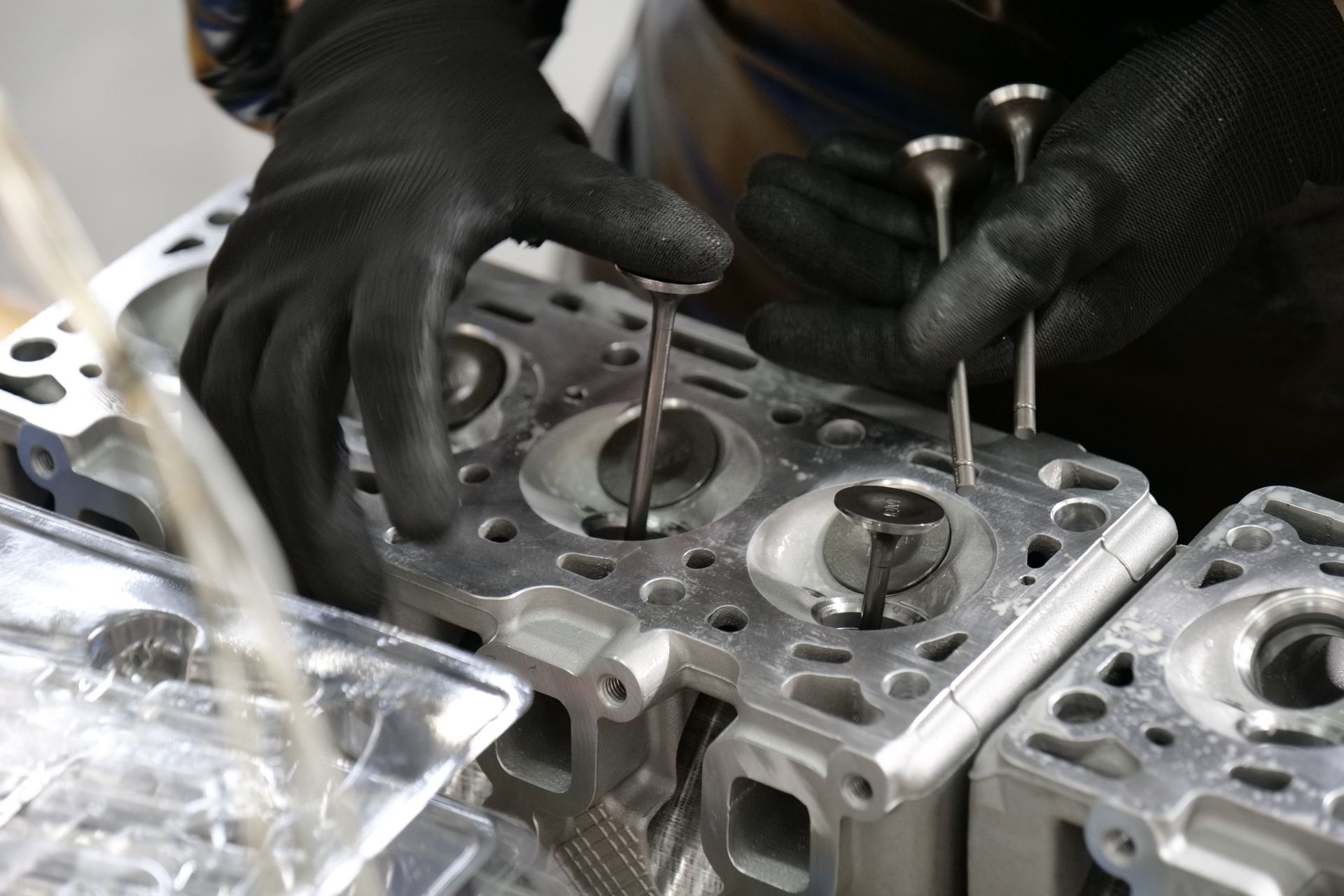 Hände einer Fachkraft bei präziser Arbeit an Motorbauteilen.