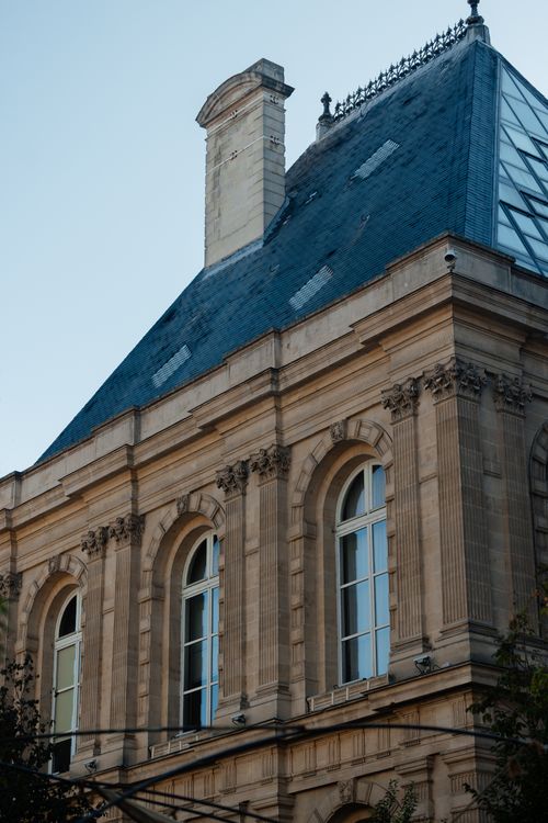 Free Elegant historic French architecture with detailed stonework and slate roof in Paris. Stock Photo