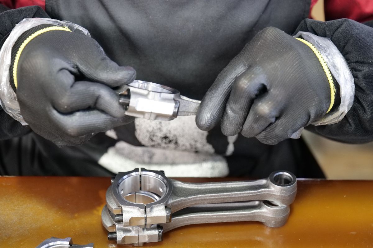 An engineer assembling a metal connecting rod with precision tools
