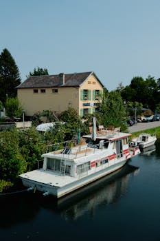 Picturesque scene of a houseboat moored on a tranquil canal in rural France by a charming house.