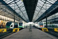 Wide-angle view of Helsinki's central train station platform with multiple trains and open roof structure.