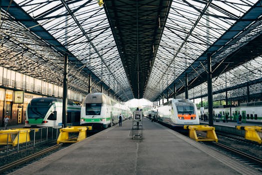Wide-angle view of Helsinki's central train station platform with multiple trains and open roof structure.