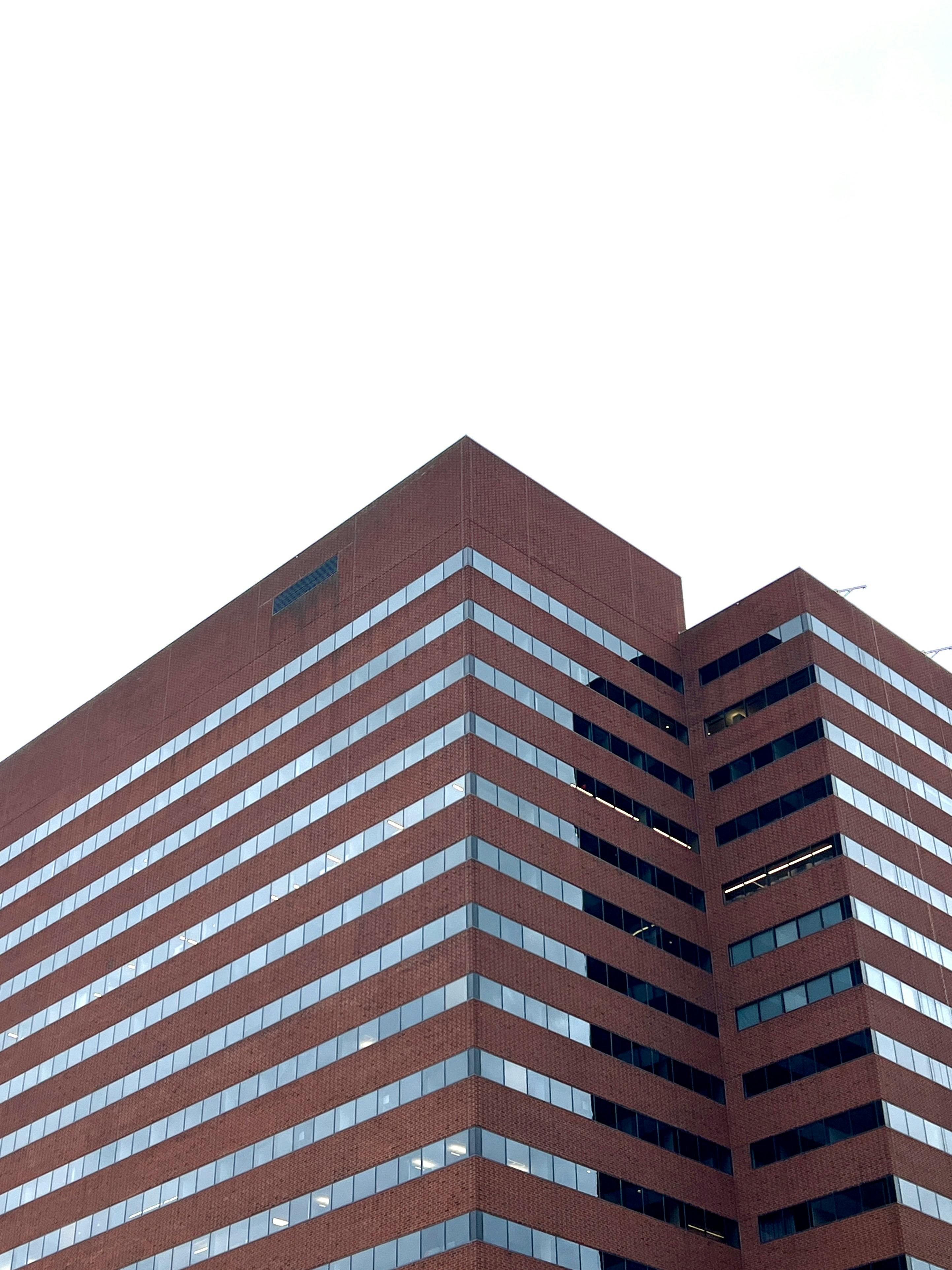 Kostnadsfria En modern höghuskontorsbyggnad med röda tegelstenar mot en klar himmel. Stock foto