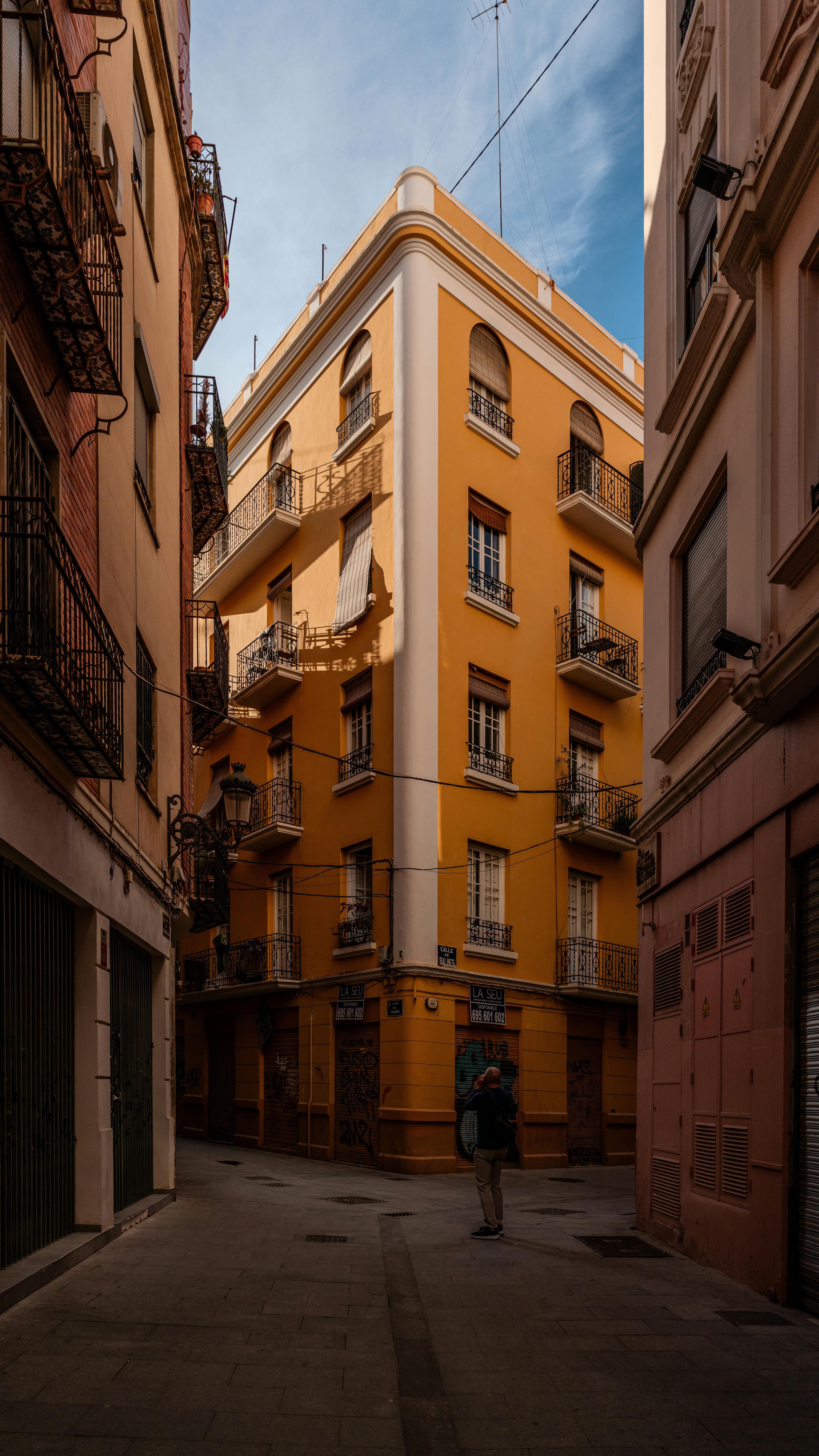 A vibrant street scene featuring a warm-toned apartment building in a European alley.