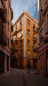 A vibrant street scene featuring a warm-toned apartment building in a European alley.