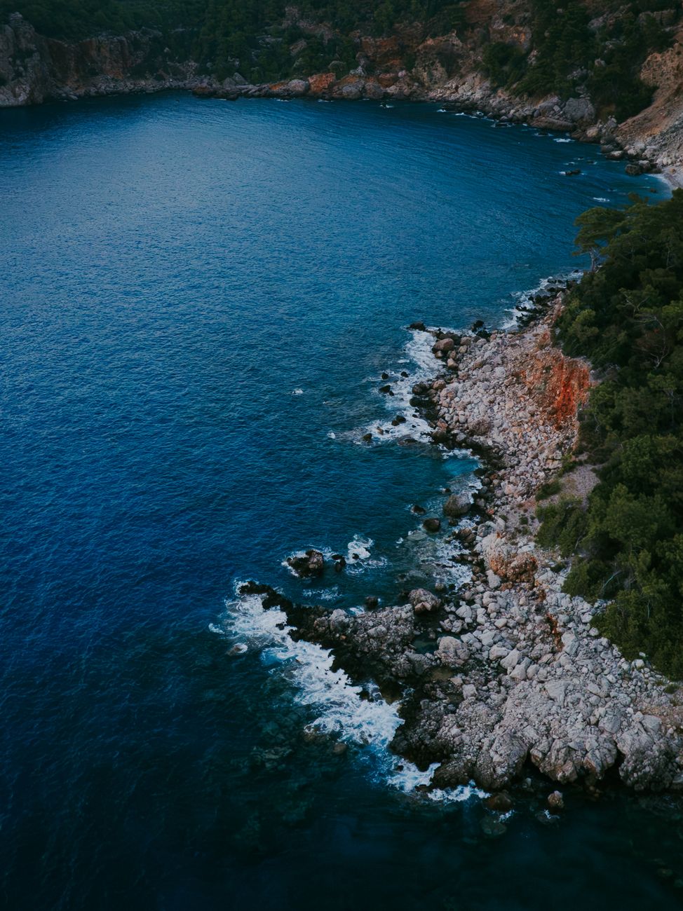 A captivating aerial view of the rocky coastline in Antalya, Turkey, with vibrant blue waters.