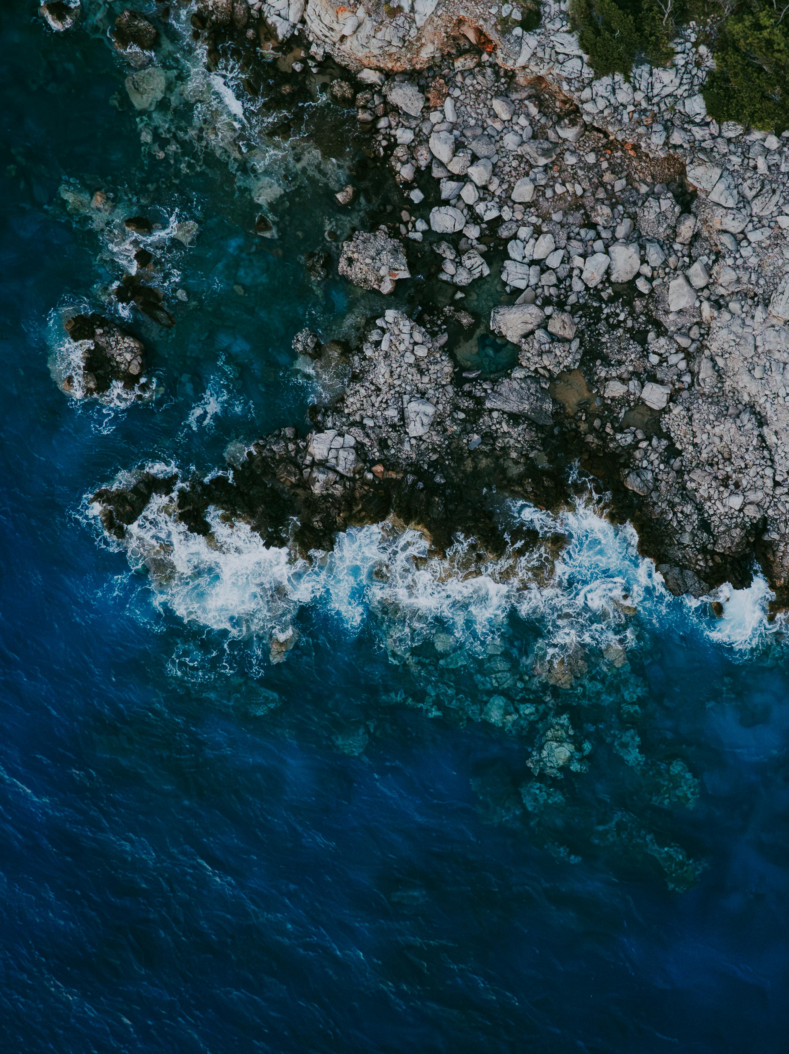 Stunning aerial capture of rocky coastline meeting vibrant blue Mediterranean Sea.
