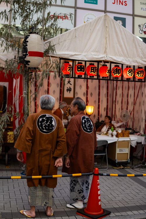 Free People in traditional attire at a vibrant Japanese street festival with lanterns and tents. Stock Photo