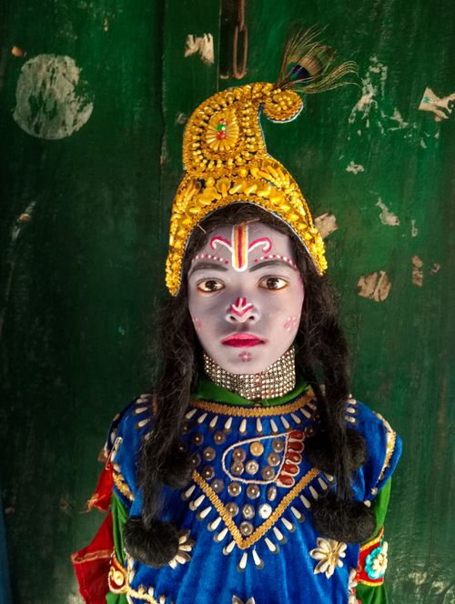 Free A child dressed in vibrant traditional Indian costume with face paint, posing indoors. Stock Photo