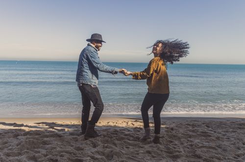 Free Couple holding hands on a sunny beach, embracing love and joy. Stock Photo