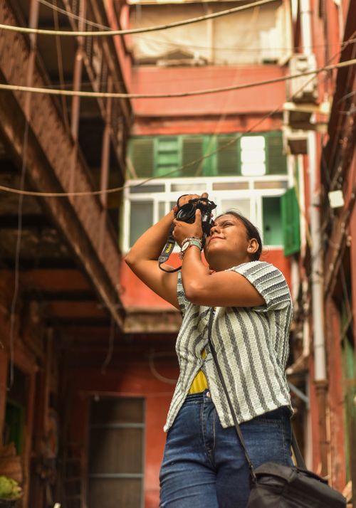 Free Female photographer exploring and capturing unique architectural details in a vibrant alley in Kolkata, India. Stock Photo