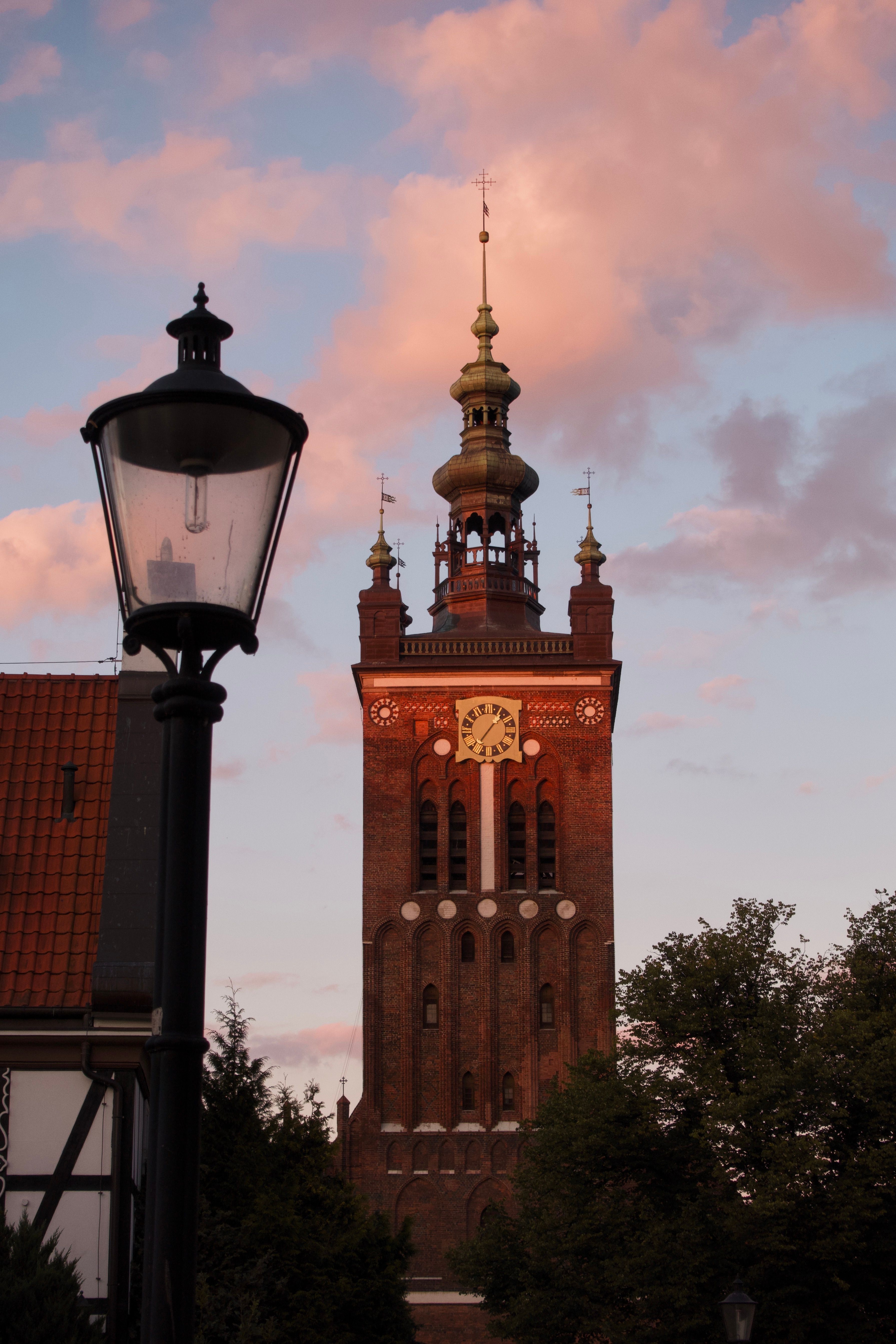 St. Mary's Church tower in Gdańsk during sunset with warm skies.