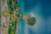 白天拍摄的鸟瞰图令人惊叹，一座桥横跨蓝色水域，沿岸是郁郁葱葱的绿色植物