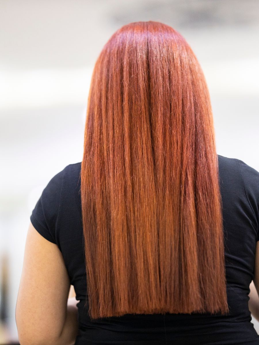 Cabelo liso tingido de ruivo cobre, visto de costas em ambiente de salão