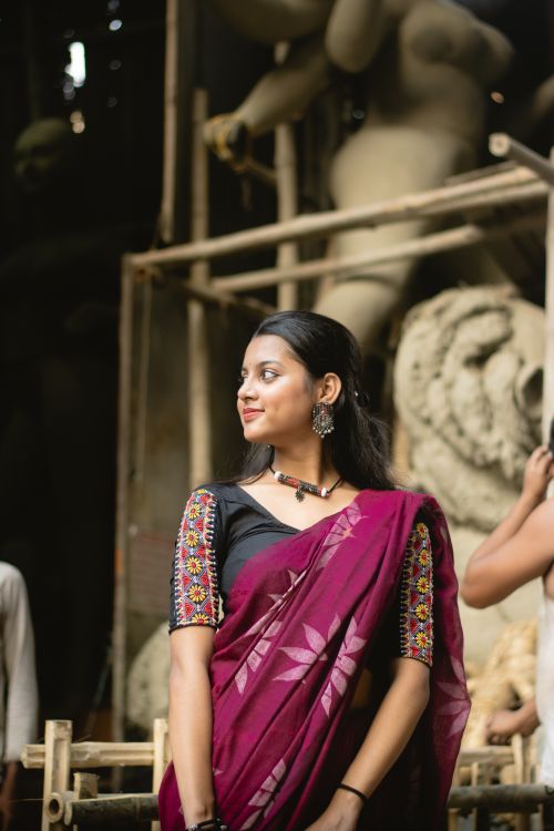 Free Elegant woman in traditional sari standing amidst sculptures in a dimly-lit artisan workshop. Stock Photo