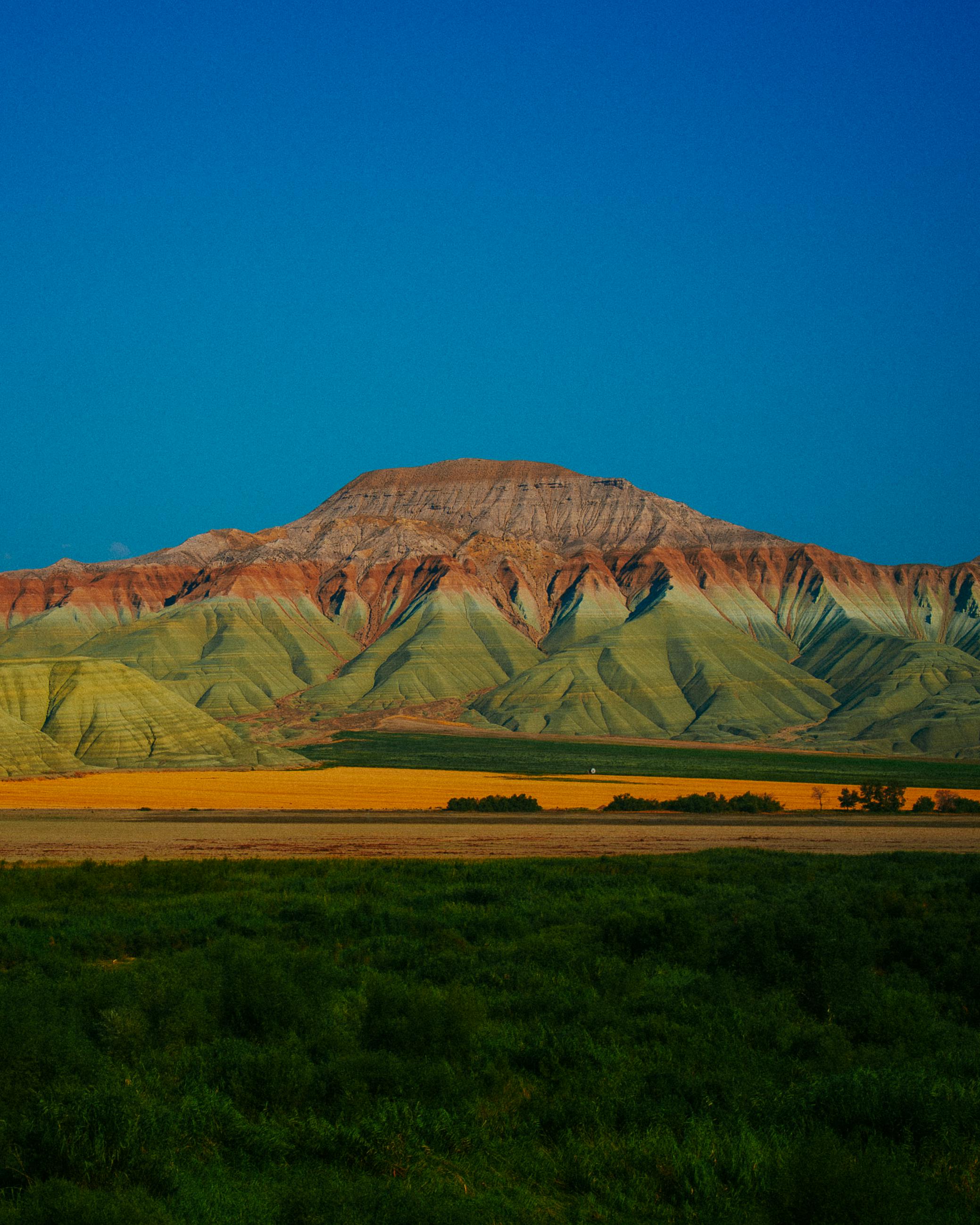 Beautiful landscape of colorful layered mountains with clear blue sky in the background.