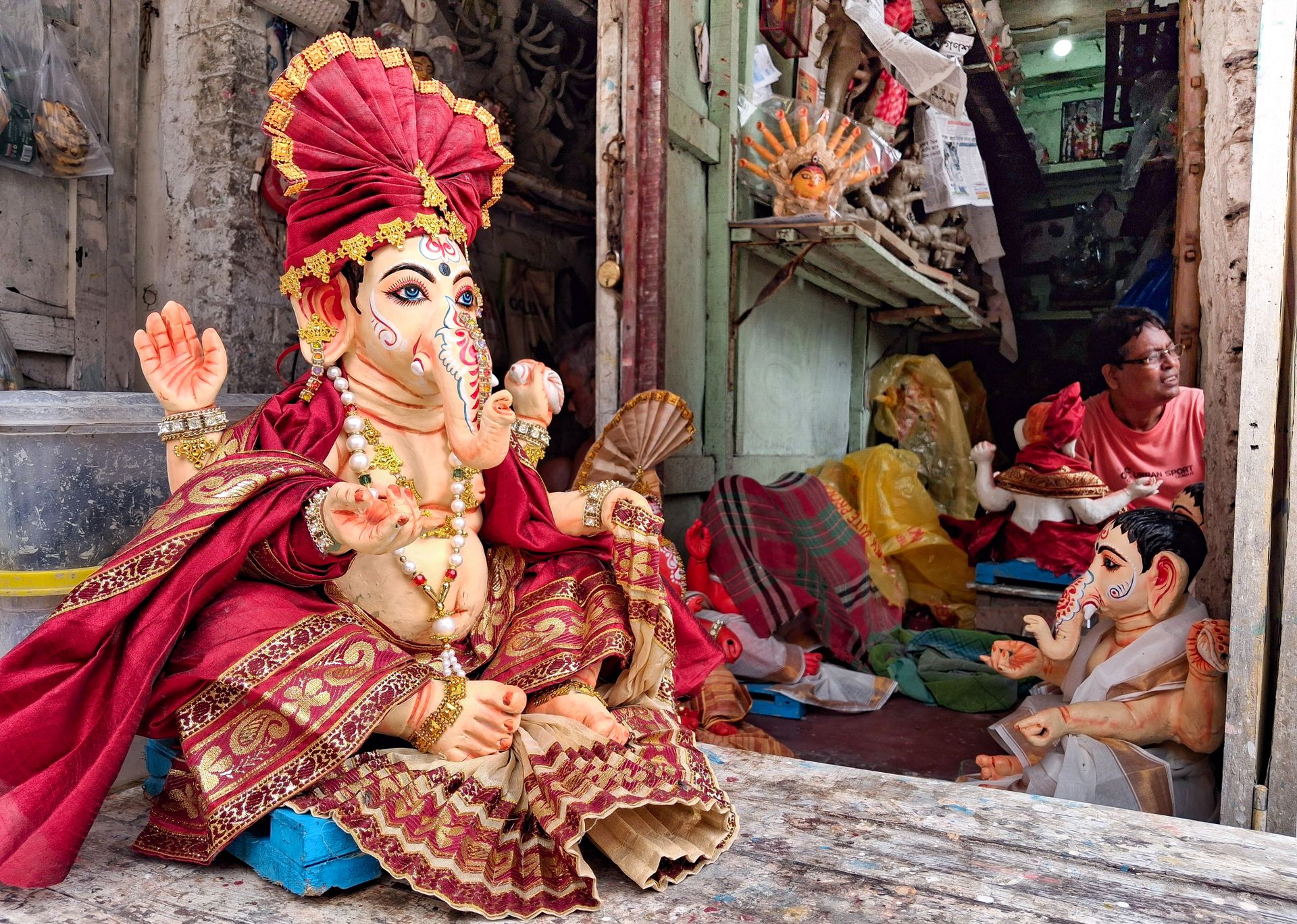 Artisan crafting Ganesh idols in a Kolkata workshop, showcasing traditional artistry and vibrant designs.