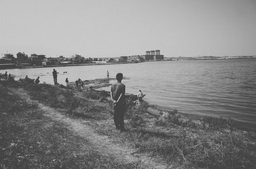 Free Monochrome scene of people enjoying a lakeside view with distant cityscape. Stock Photo