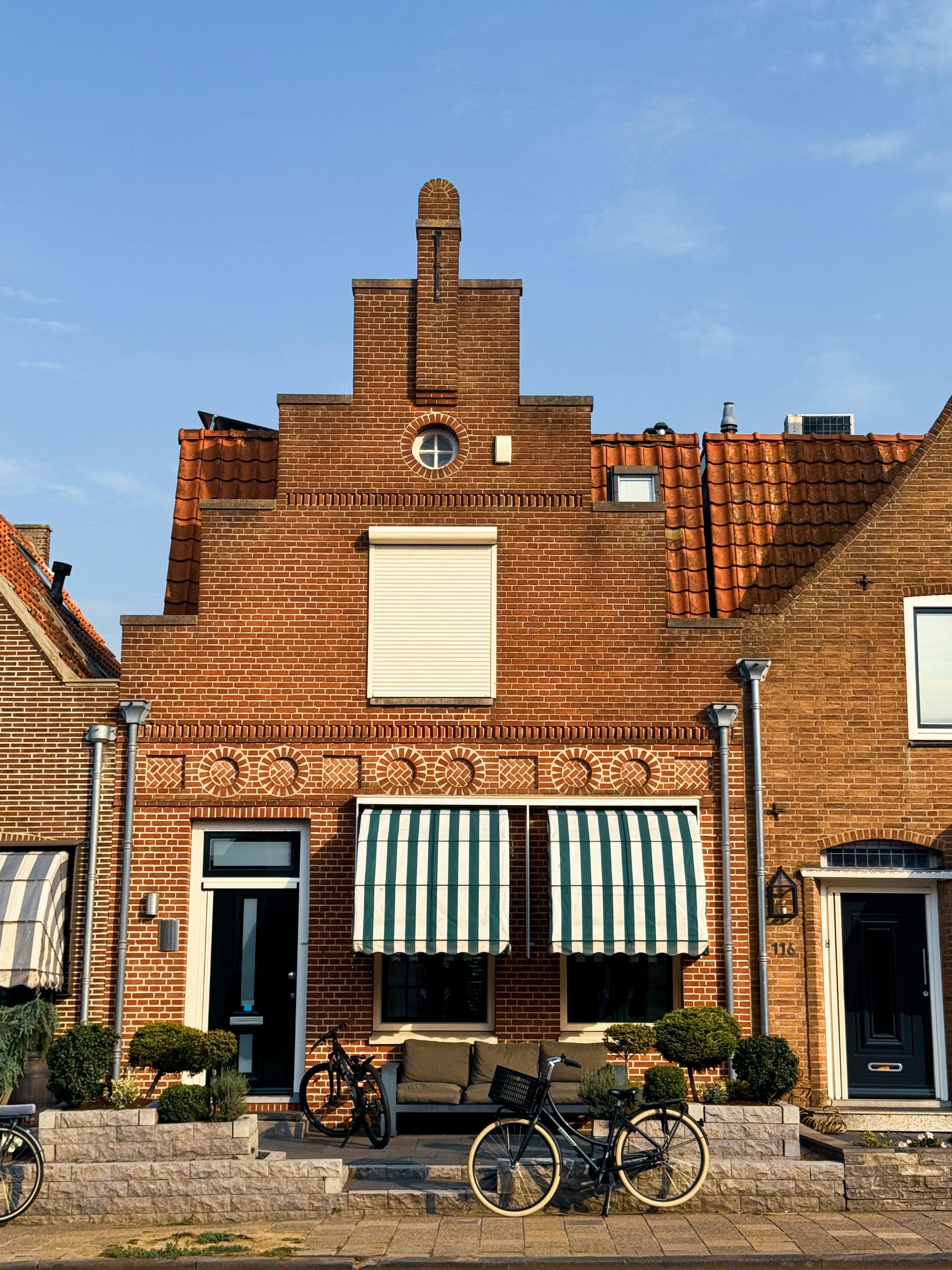 Quaint brick houses with striped awnings and bicycles in Volendam, Netherlands.