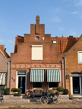 Quaint brick houses with striped awnings and bicycles in Volendam, Netherlands.