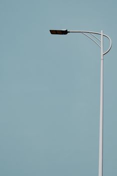 A minimalist street light stands against a clear blue sky, showcasing simplicity.